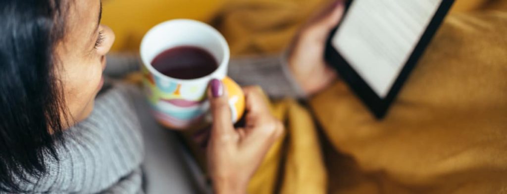 vrouw leest ebook terwijl ze koffie drinkt